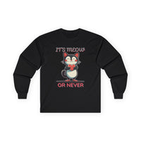 Black long-sleeve Valentine's shirt featuring an adorable cat-themed design. The front showcases a cute black and white cartoon cat with rosy cheeks, holding a red heart and smiling sweetly. Above and below the cat, playful text reads "IT'S MEOW OR NEVER" in a fun, romantic font. This cat lovers' shirt is perfect for Valentine's Day, offering a charming and lighthearted way to celebrate love and affection with a feline twist.